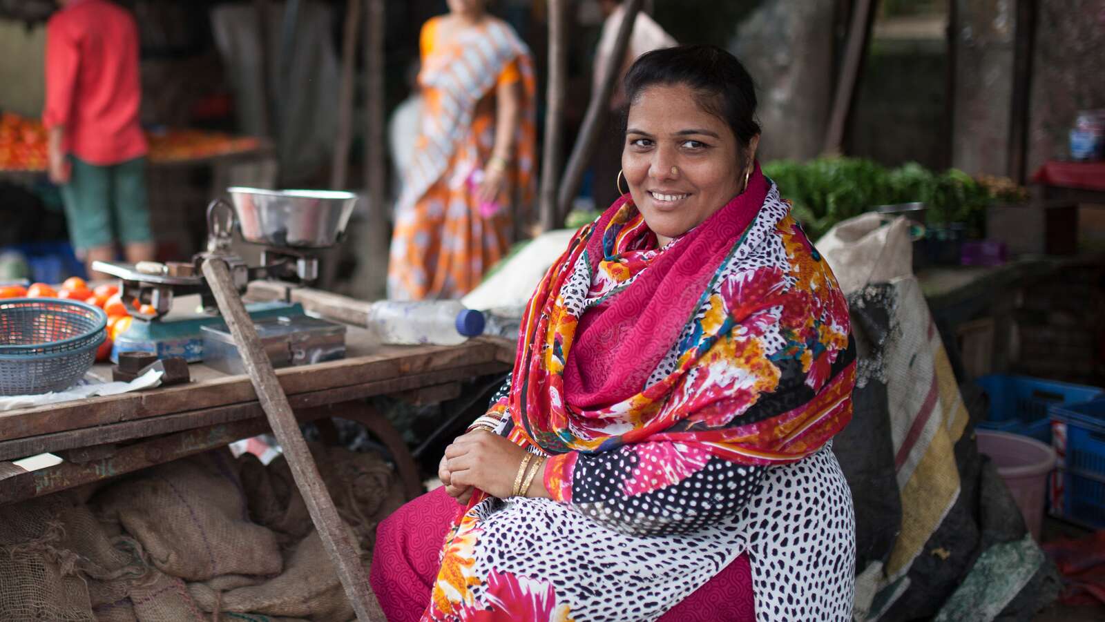 A woman sits in her street vendor shop in India.