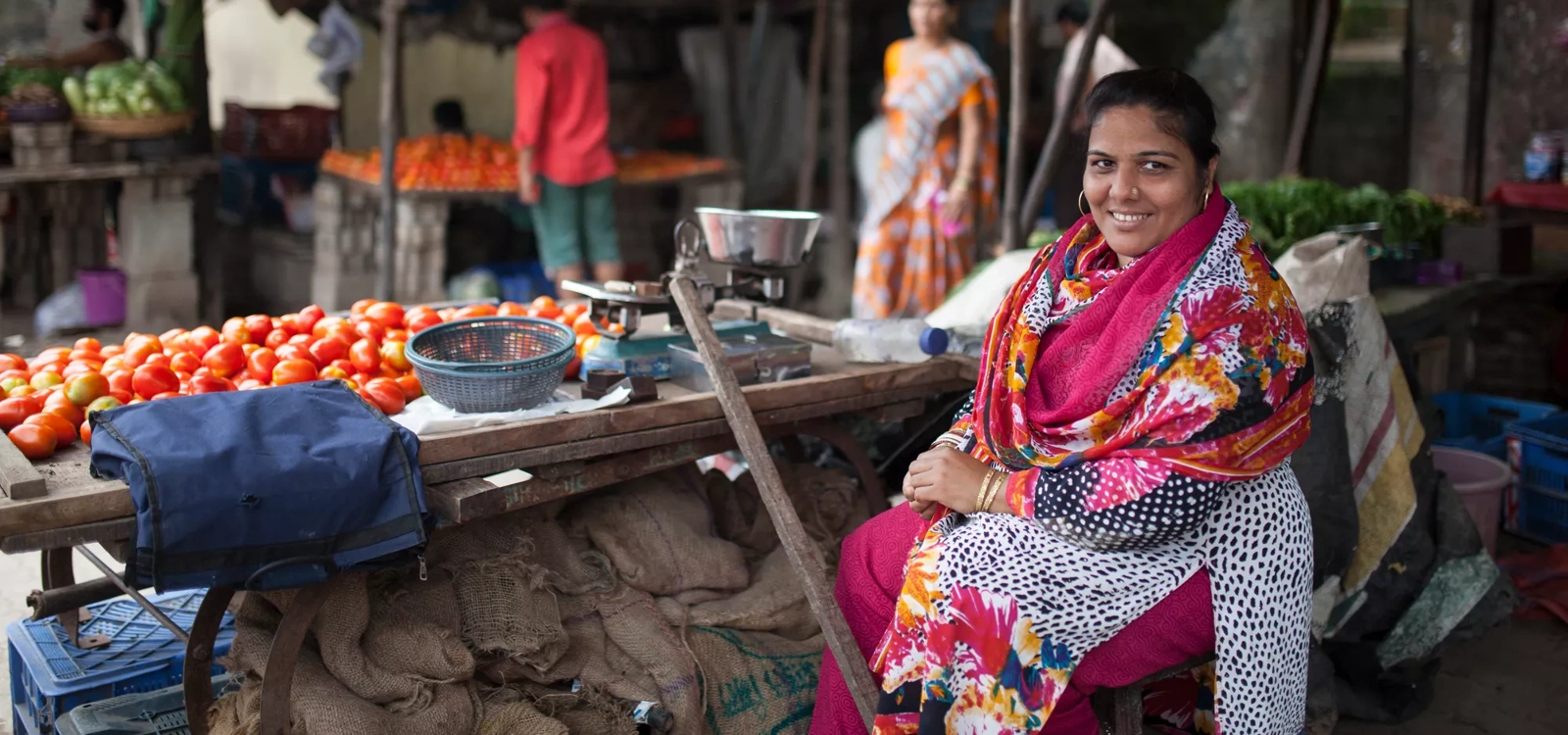 A woman sits in her street vendor shop in India.