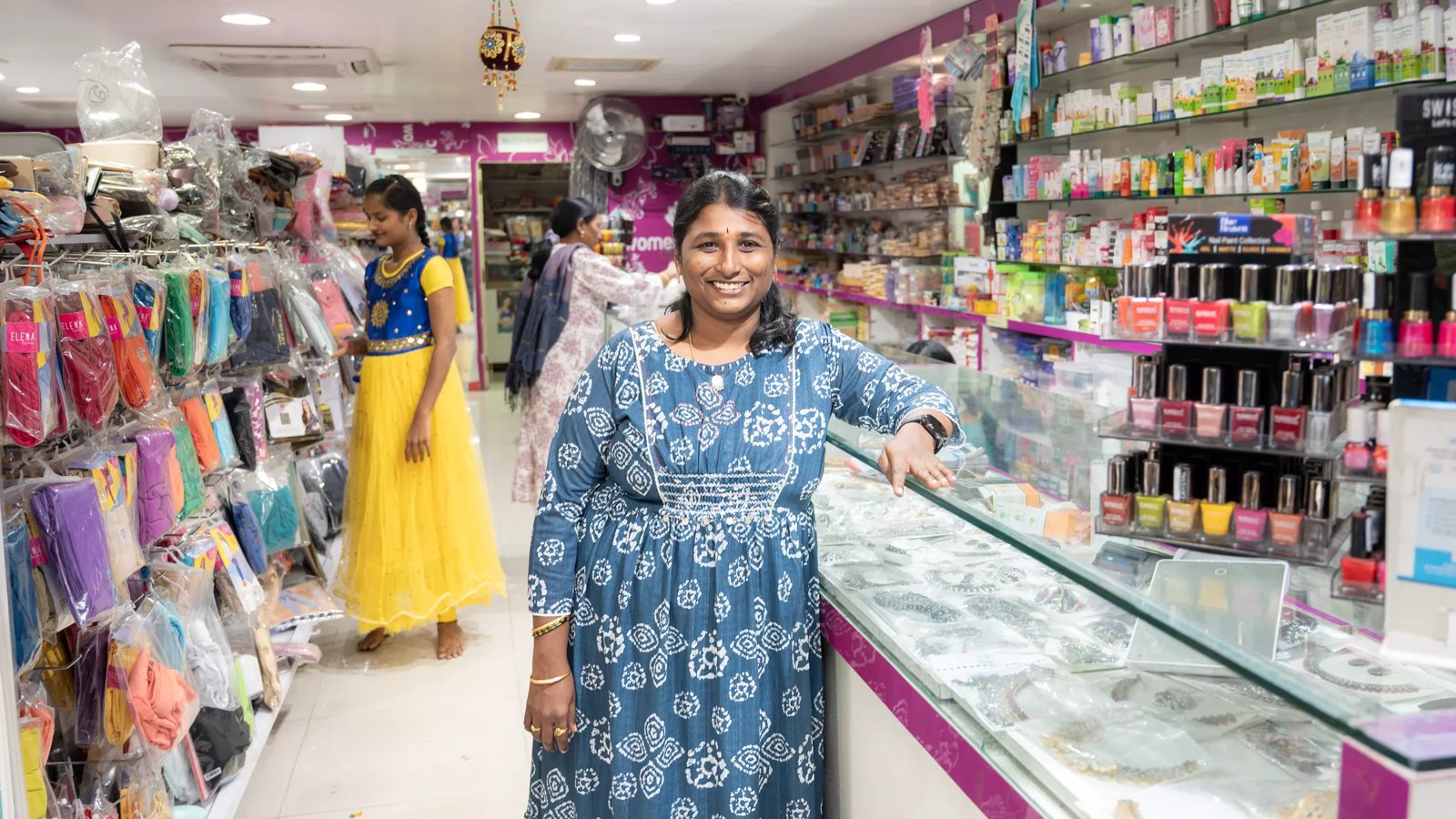 A Indian woman stands in her shop.