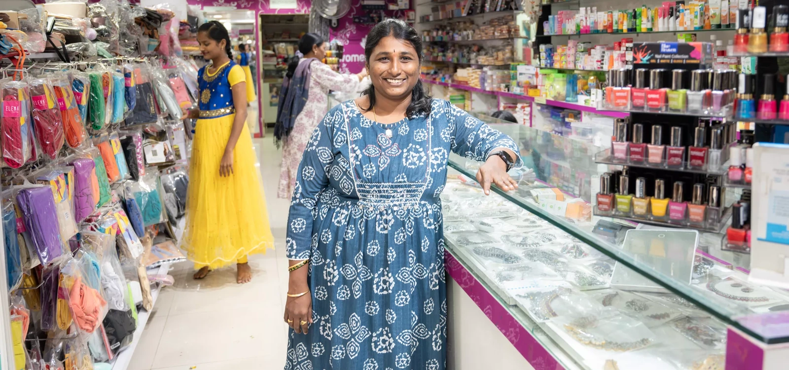 A Indian woman stands in her shop.