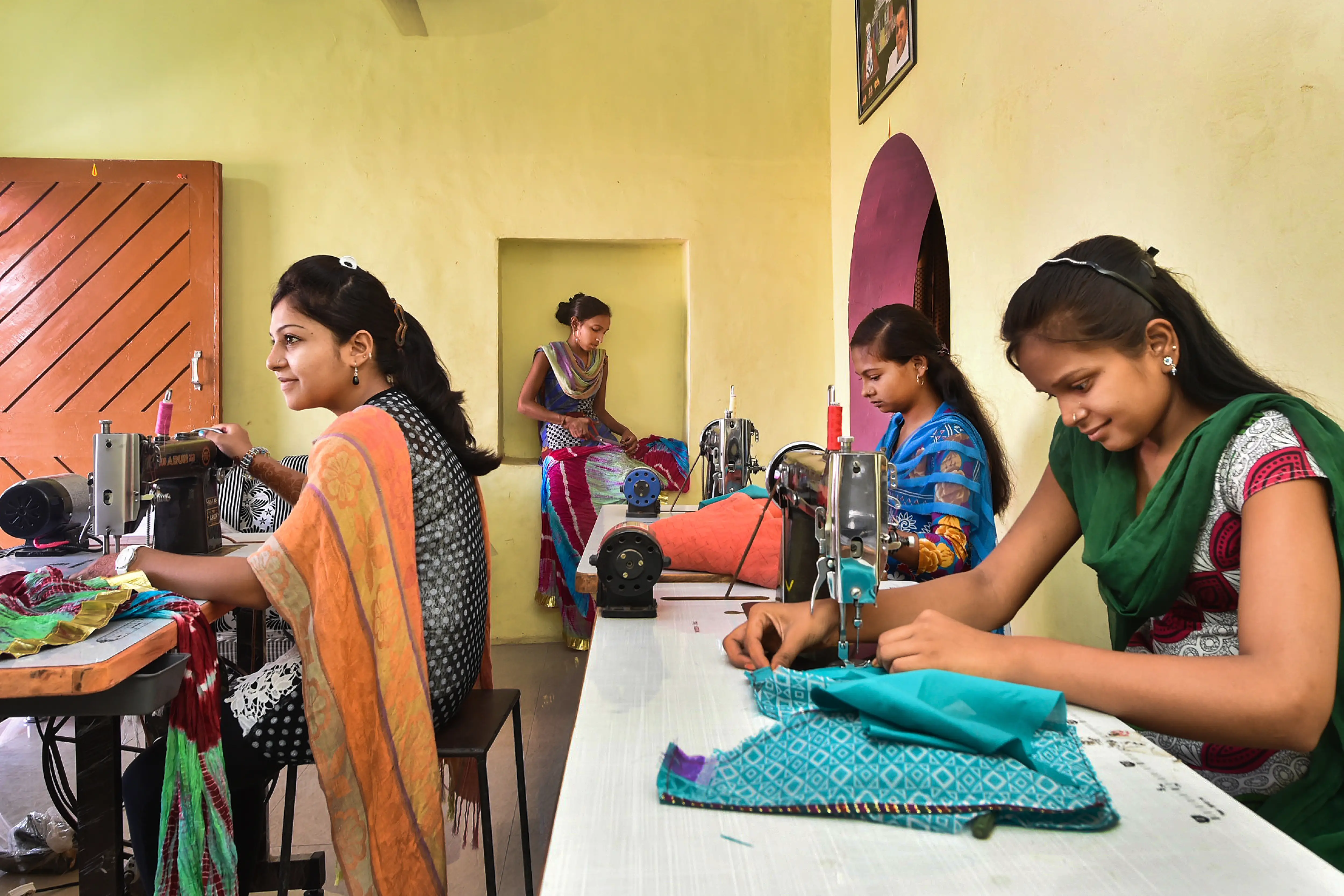 Women in a colorful room using sewing machines.