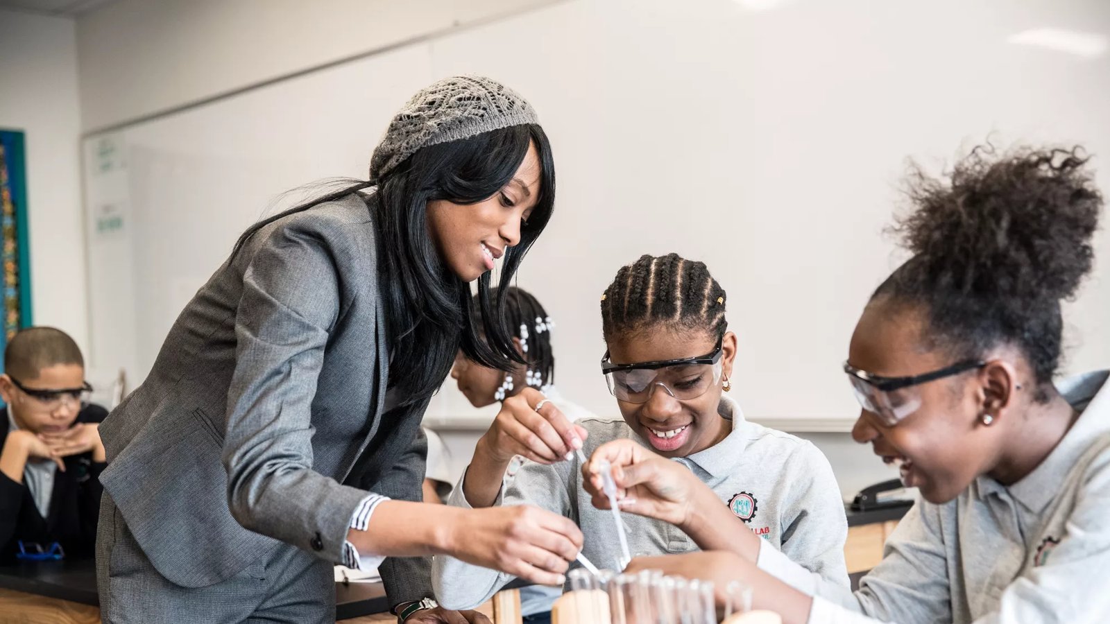 A teacher assists two students with their classroom chemistry project.