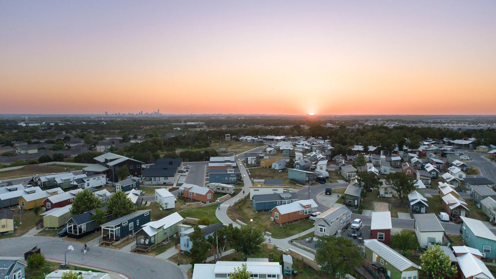 Aerial shot of Community First! Village against the backdrop of the Austin Skyline at sunrise.