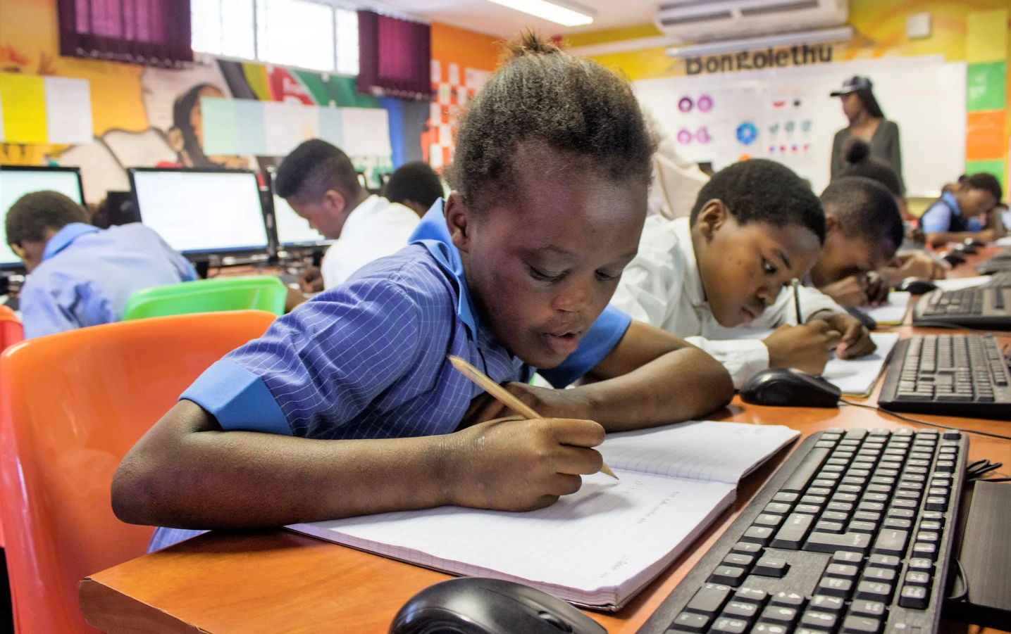 A South African girl writes in her notebook in a classroom.