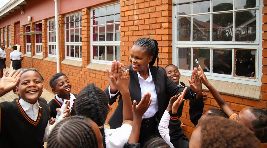 A teacher high fives with students outside a classroom.