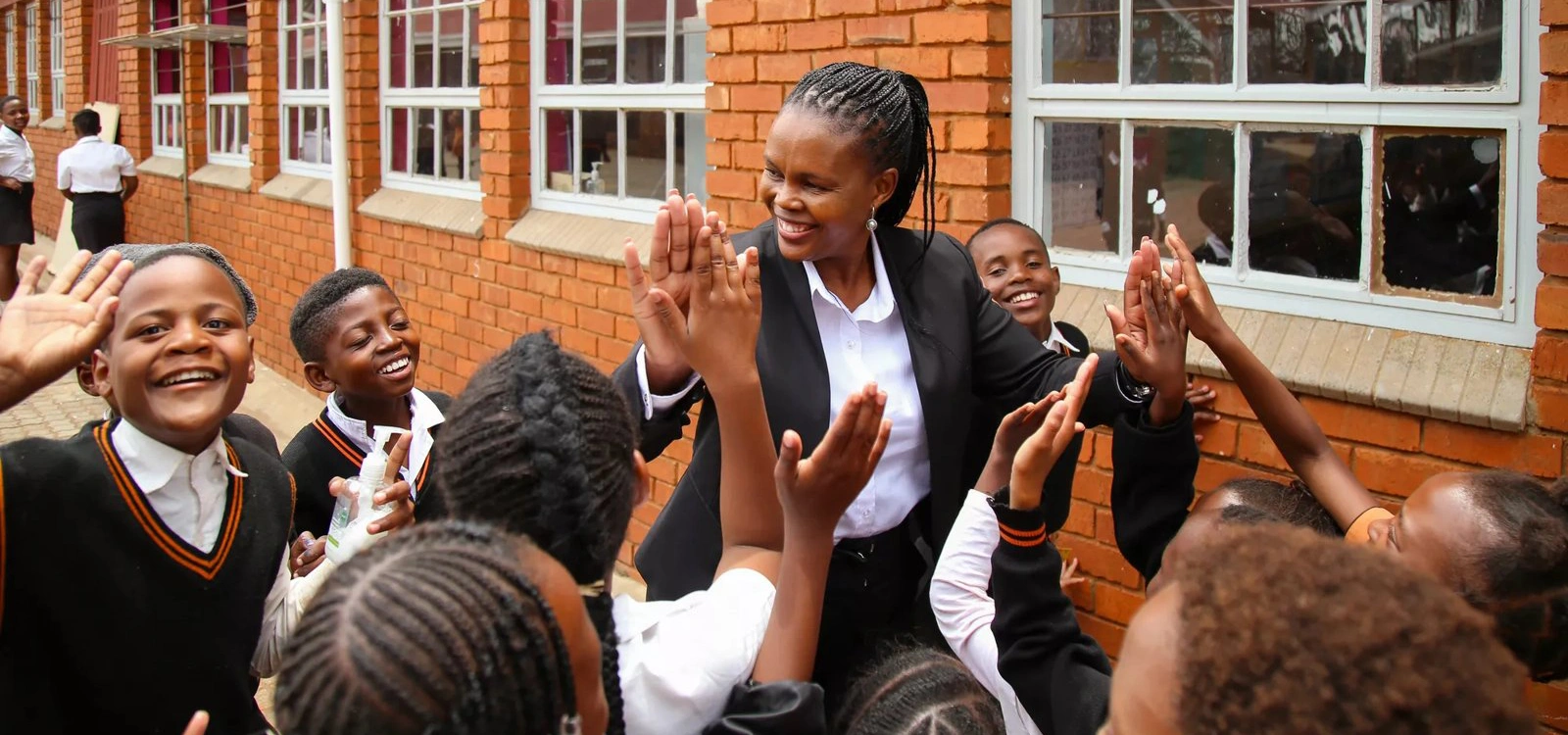 A teacher high fives students outside a classroom.