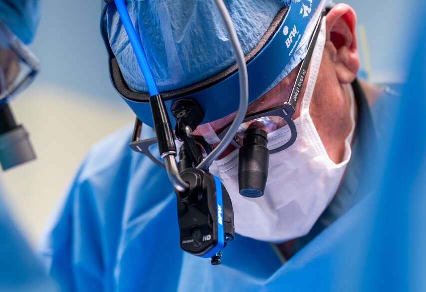 A doctor in surgical gear performs a procedure.