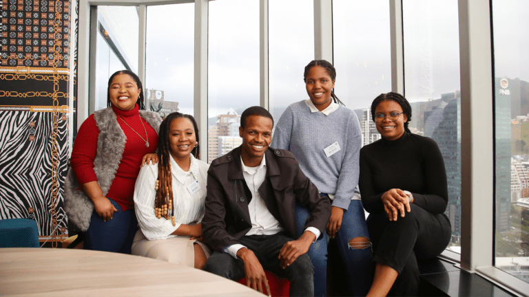 Five Dell Young Leaders alum sit together, smiling at an Alumni Networking Event.