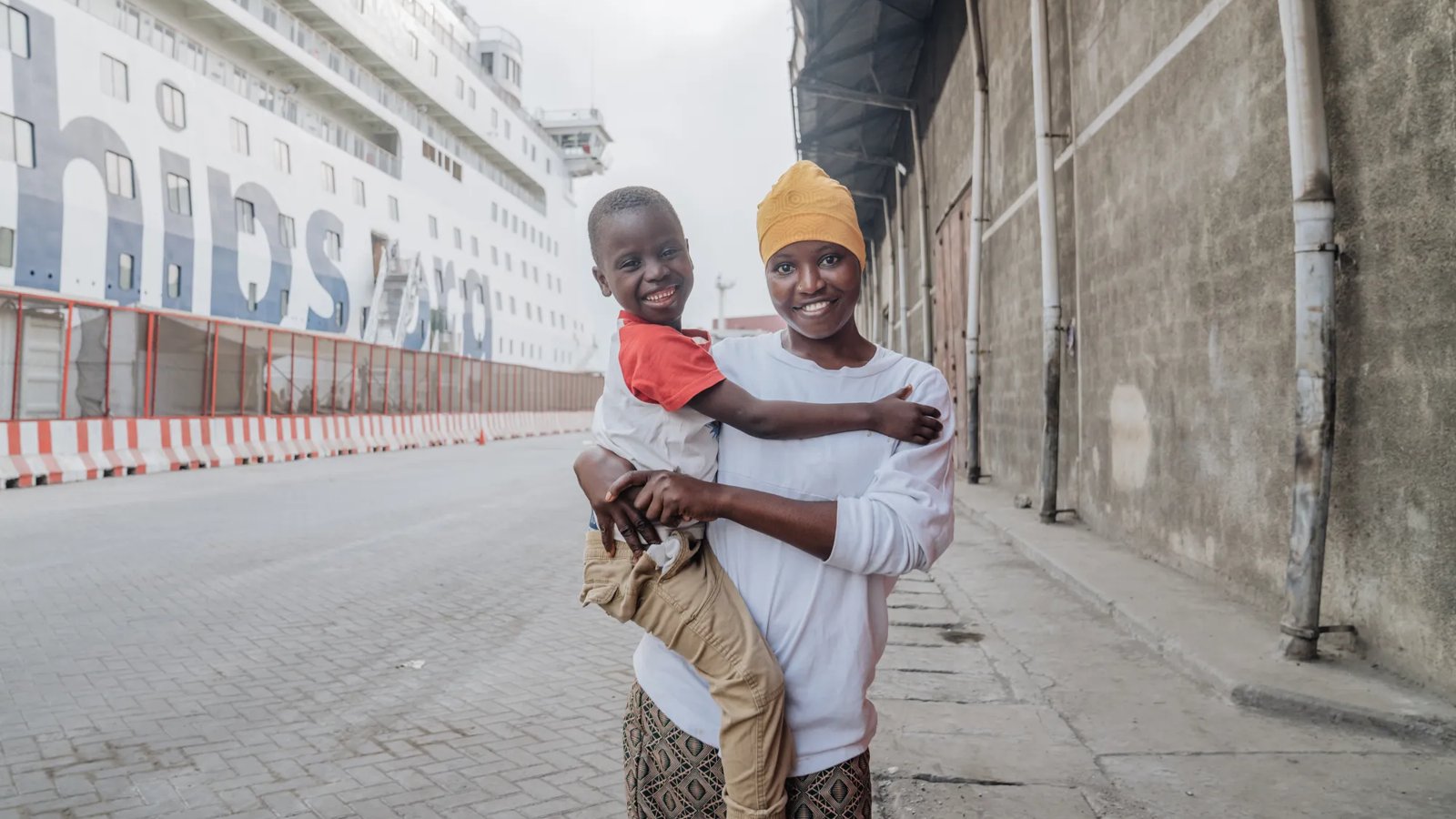 A mother and son stand outside a hospital ship in Africa.