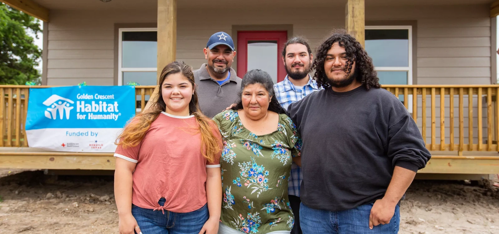 A family stands in front of their newly built home.