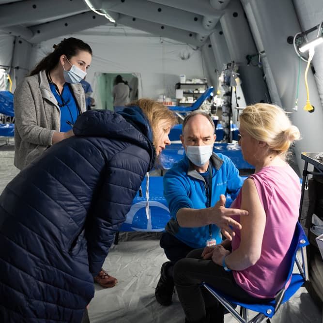 A health worker checks on a patient in a Ukraine refugee camp.