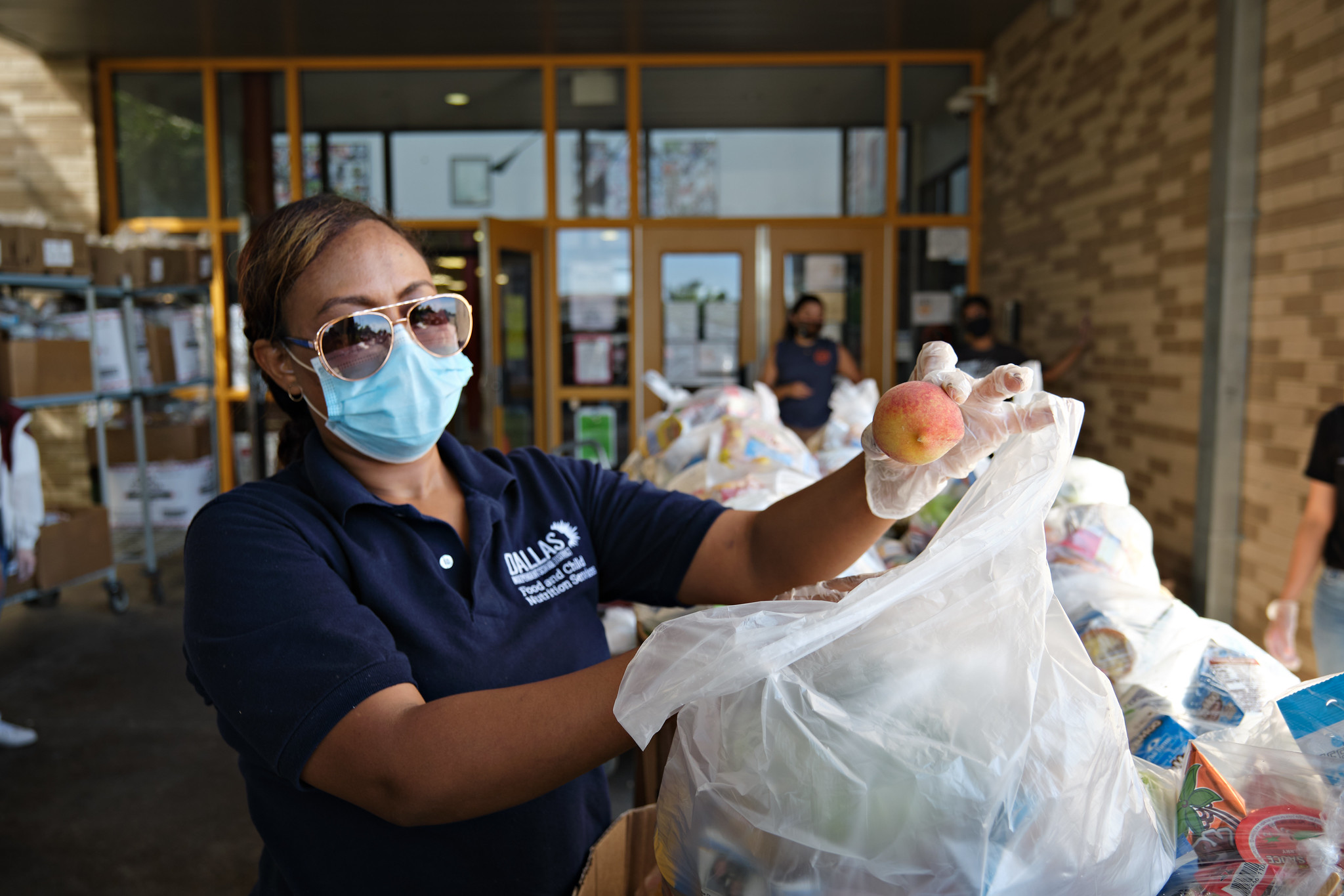 A woman bags fruit in grocery bags.