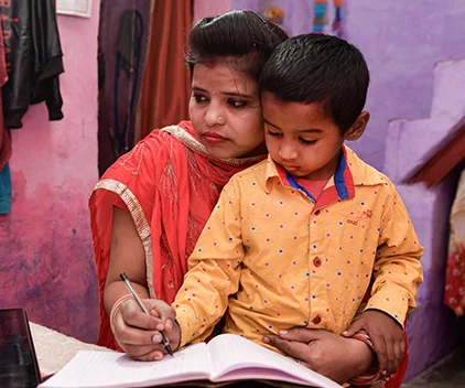 A woman helps a child with his schoolwork.