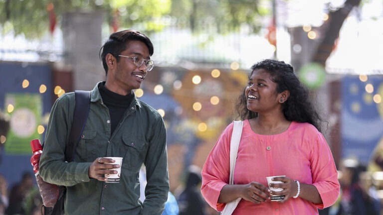 Two students walk together on a university campus.