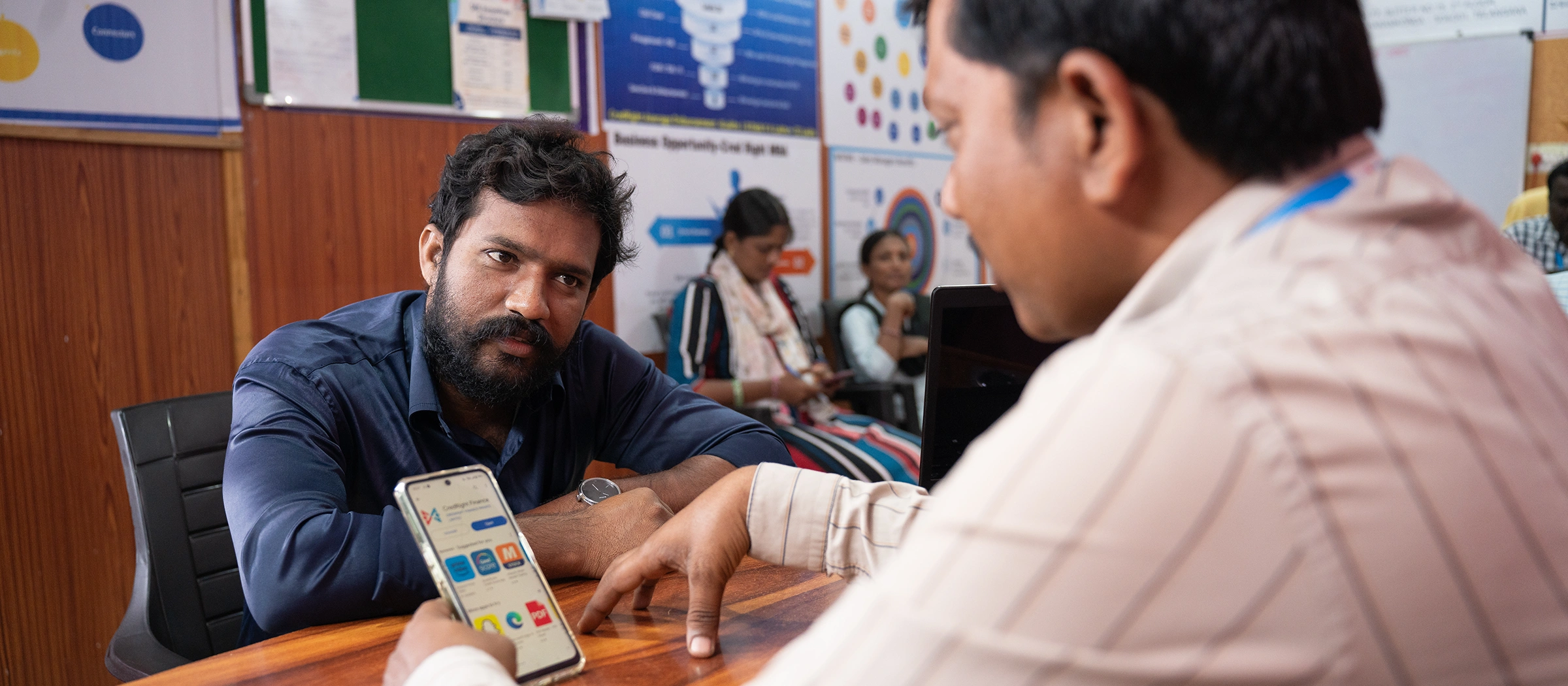 Two men look at a phone app in an office.