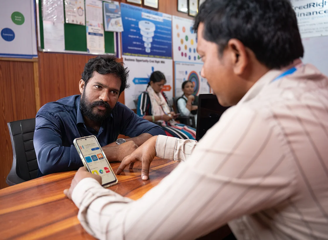 Two men look at a phone app in an office.