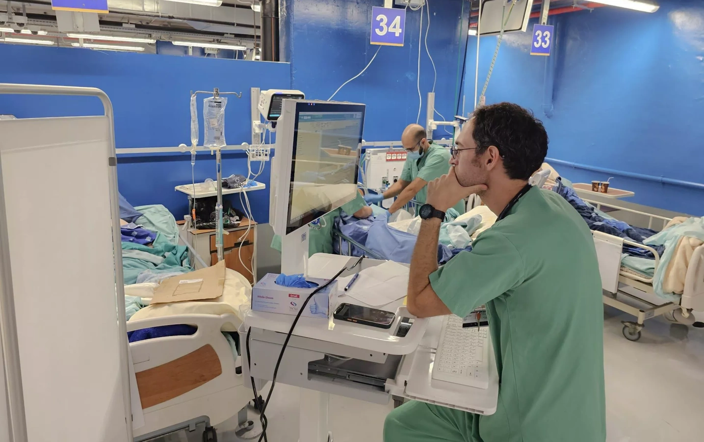 A doctor looks at a computer screen in a hospital setting.