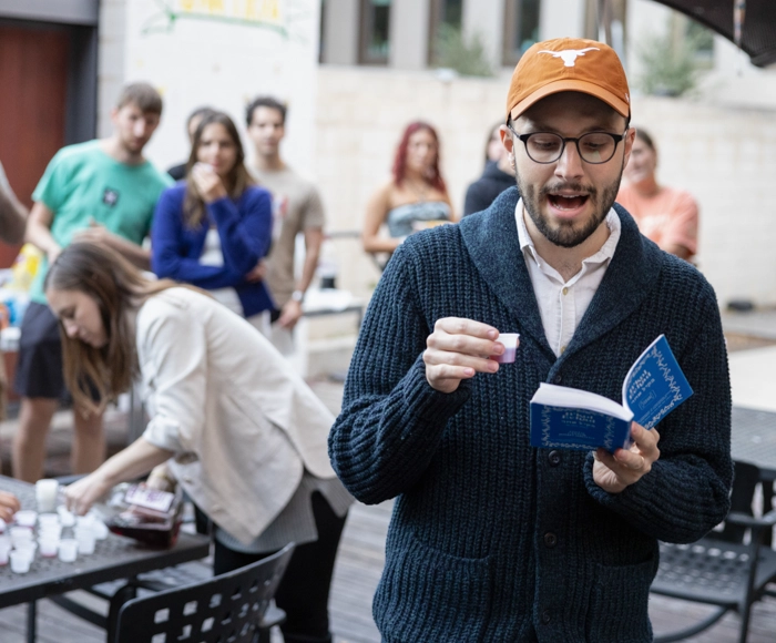 A student in a burnt orange Longhorns hat reads aloud at a Yom Kippur pre-fast event at Texas Hillel on campus.