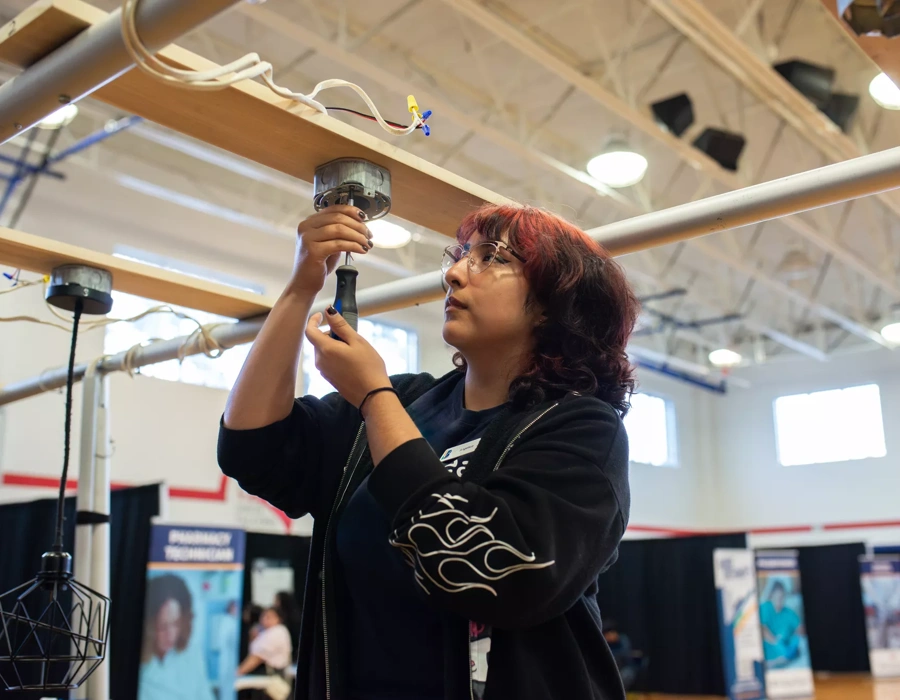 A young woman works on an electrical project at a career fair.