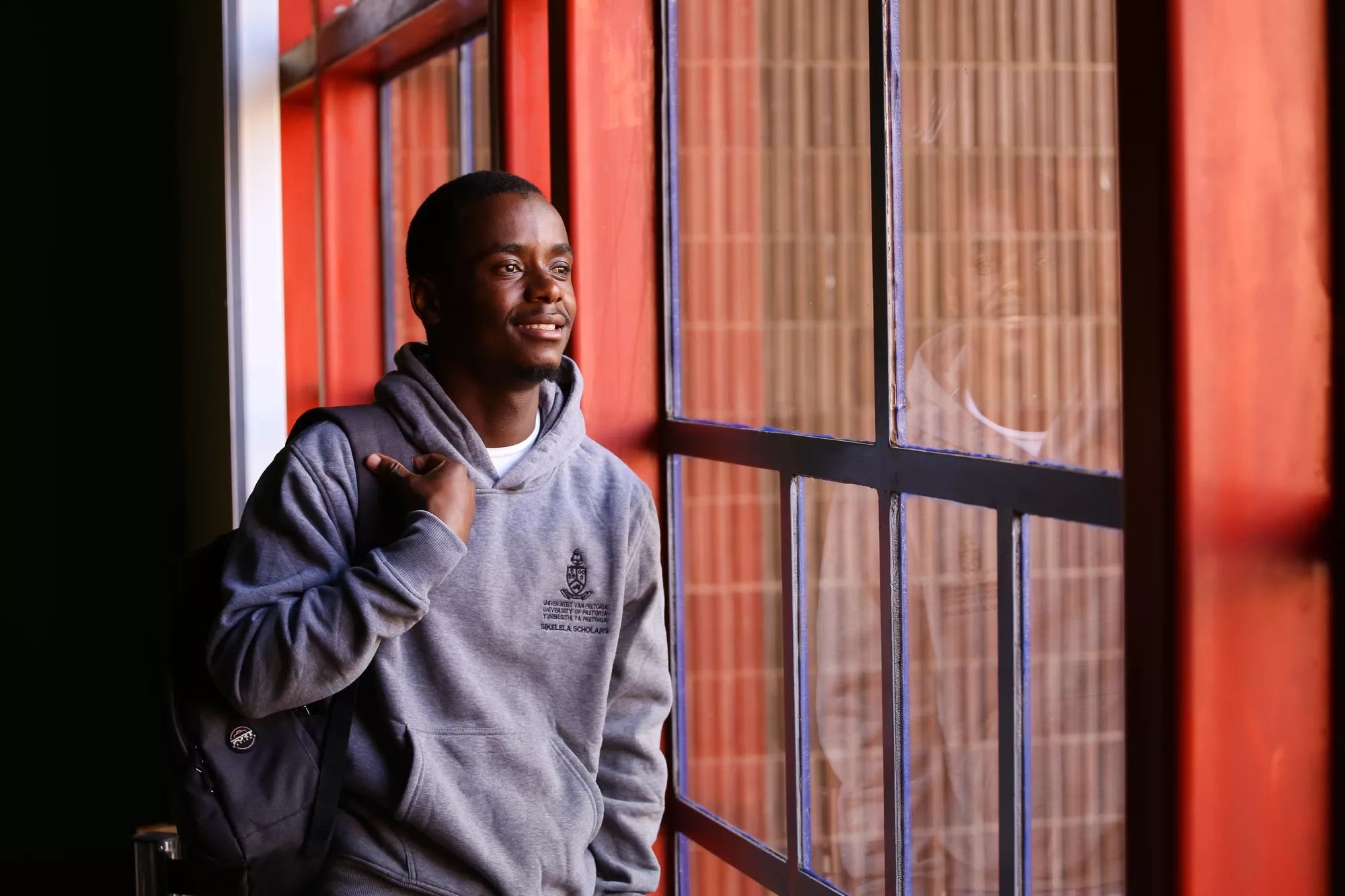 A student gazes out the window of a university building.