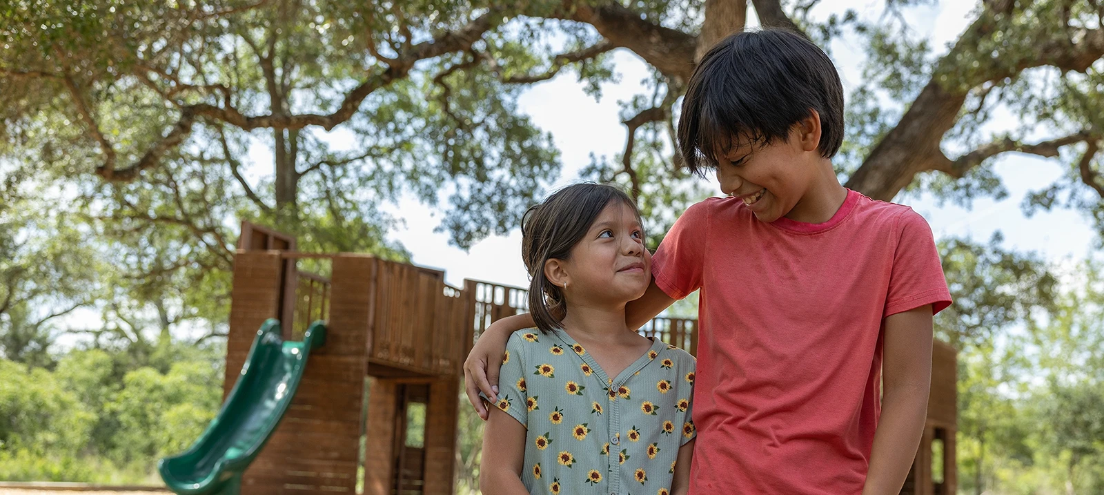 Two children look at each other with smiles on the playground.