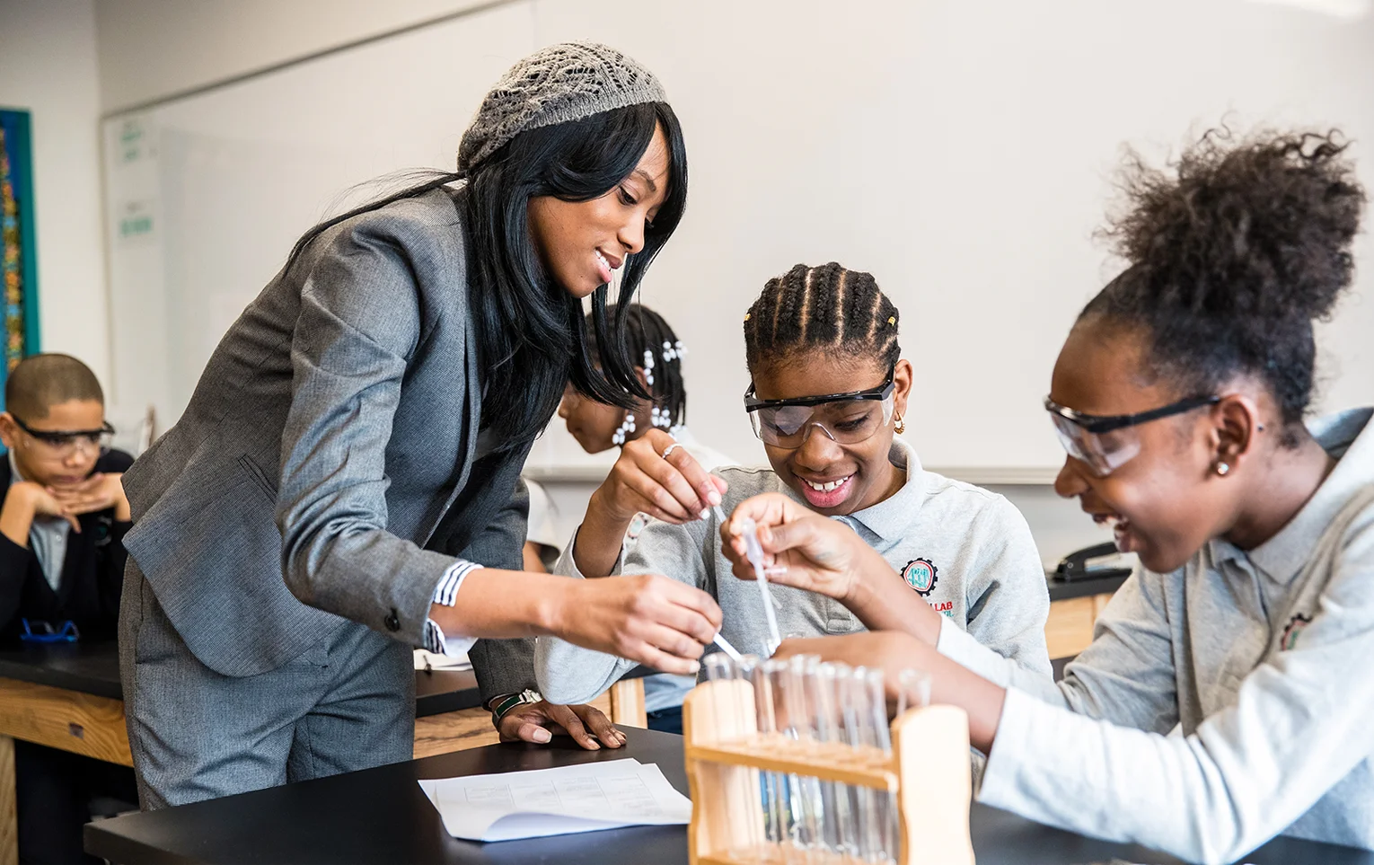 A teacher helps two students with a science experiment in a classroom.