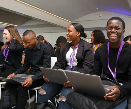 Smiling students holding laptops