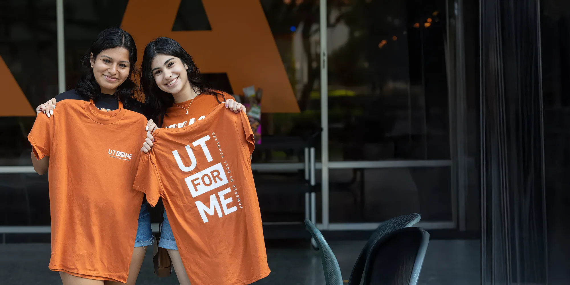 Two college students hold UT for Me t-shirts.