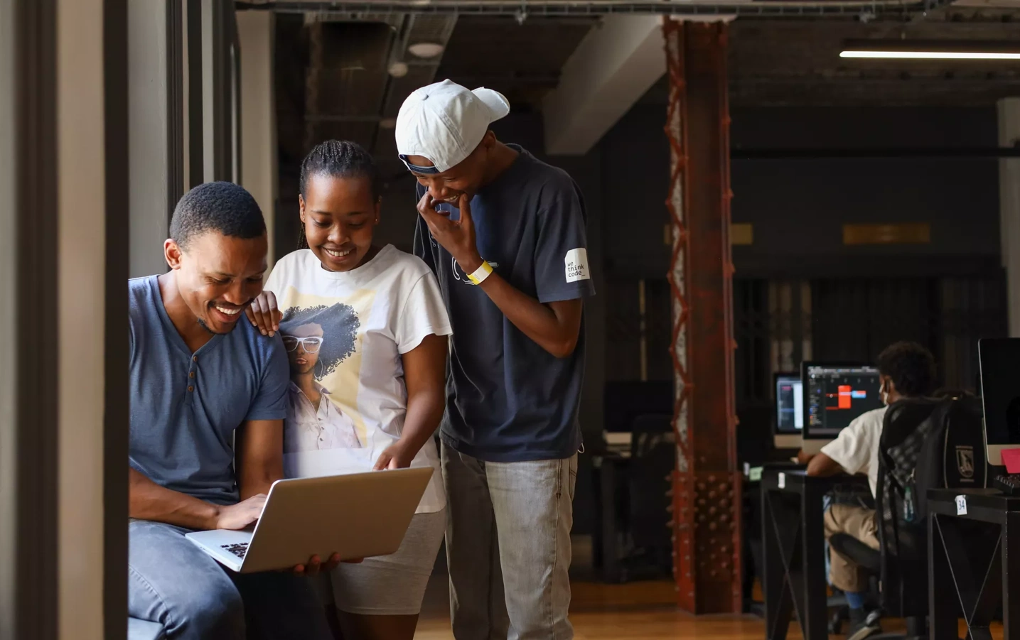 Staff and students look at a laptop in the WeThinkCode office.