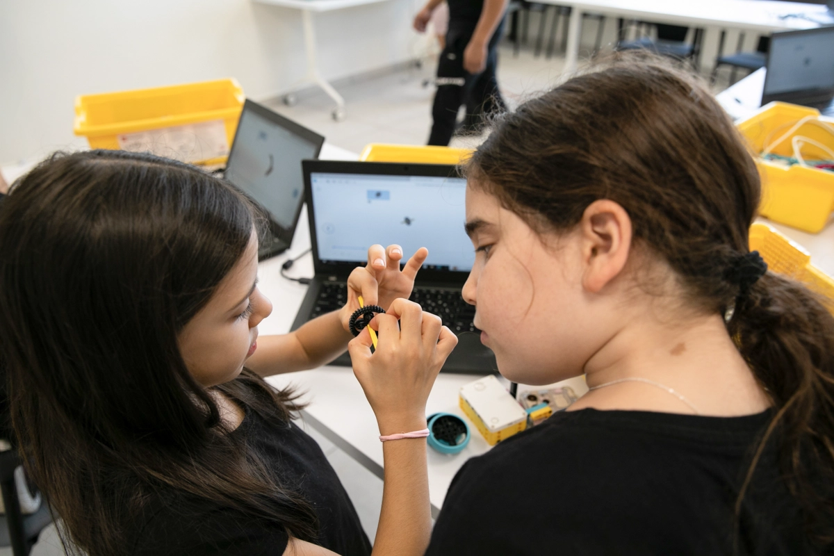 Two young girls work on a class project together in a school.