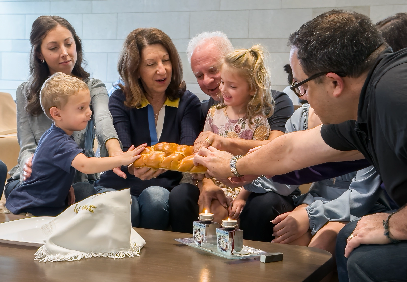 Multi-generational Jewish family celebrating Shabbat with challah bread.