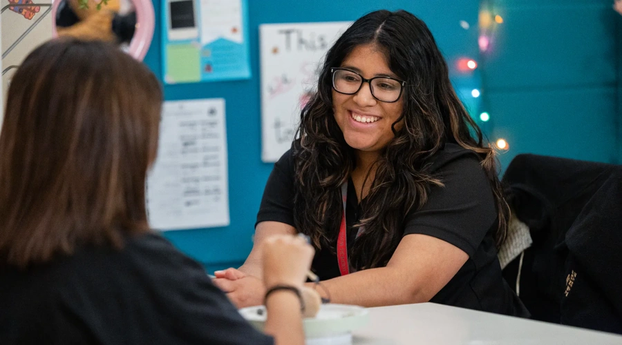 A Communities in Schools staff member smiles while meeting with a student.